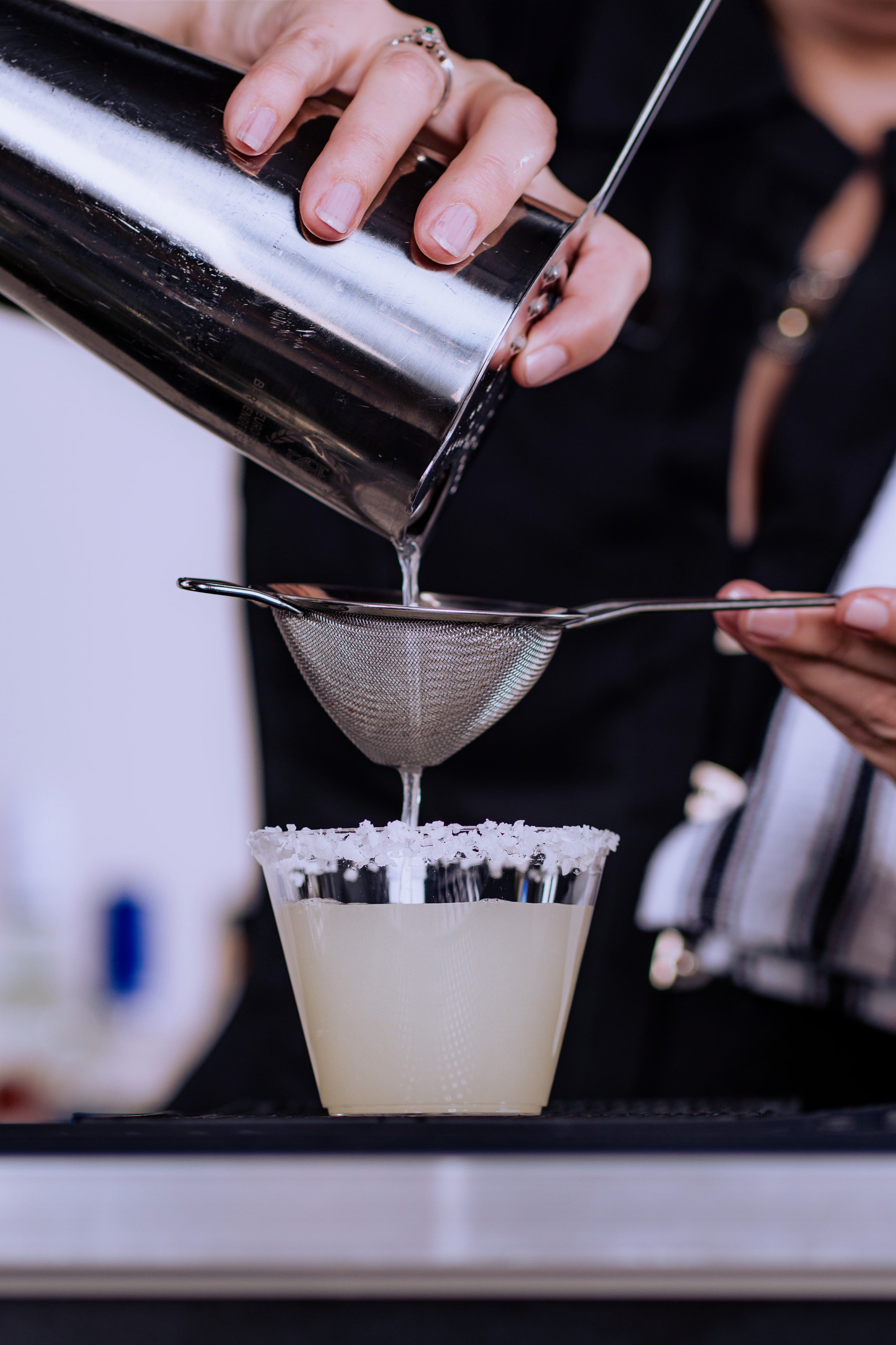 Margarita being fine-strained into a salt-rimmed glass