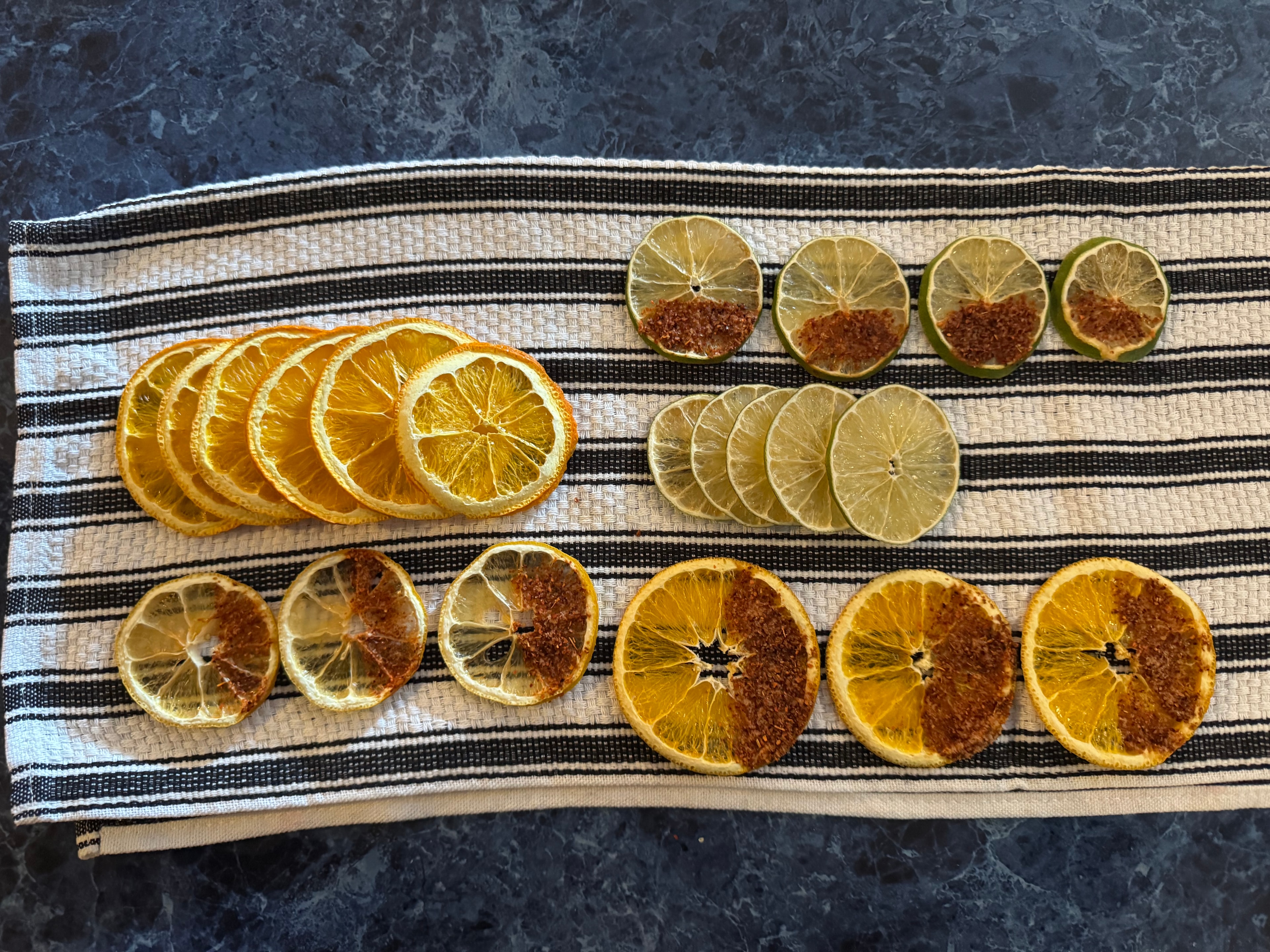 Finished dehydrated citrus garnishes laid out on a striped towel