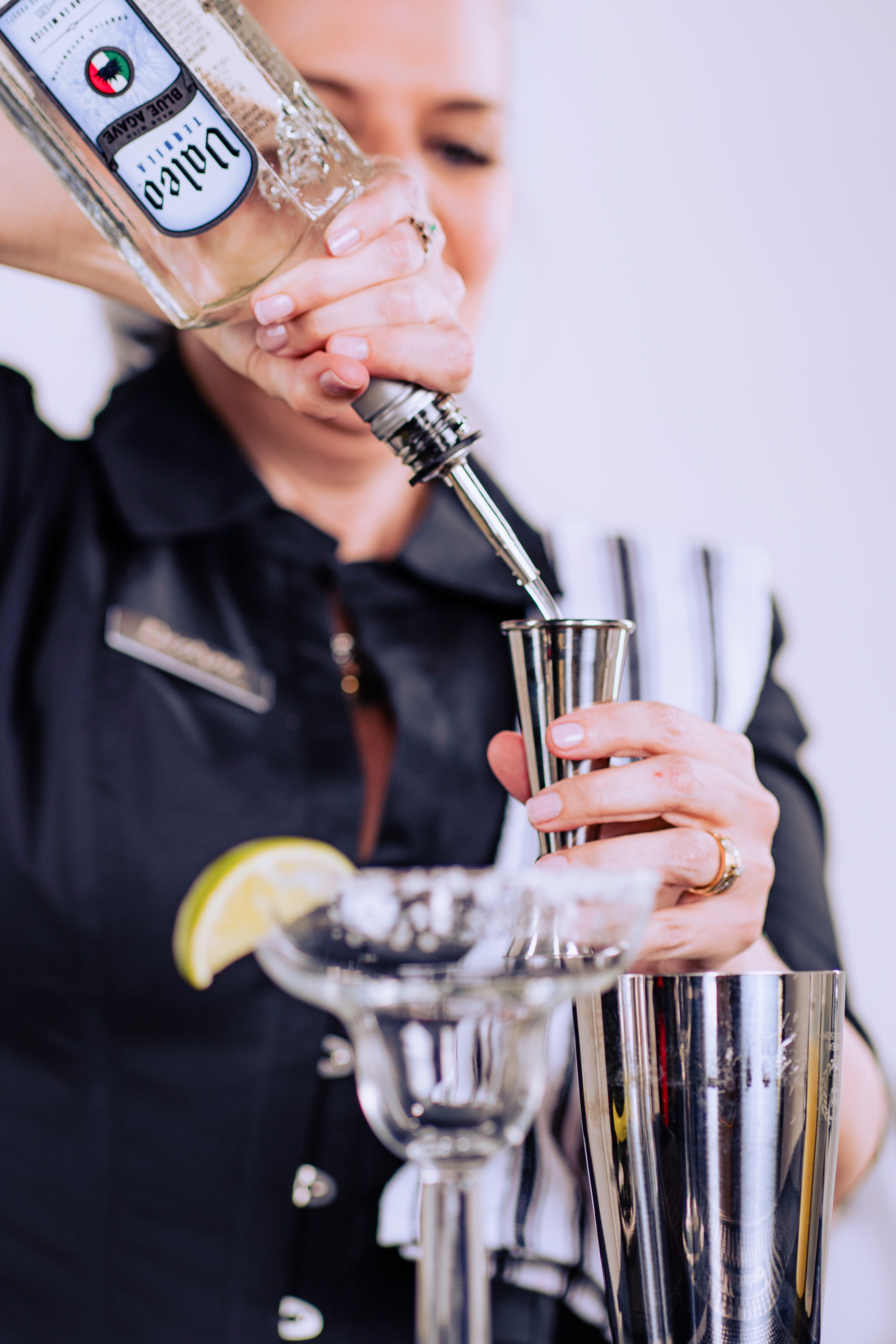 Tequila being poured into a jigger with a margarita glass in the foreground