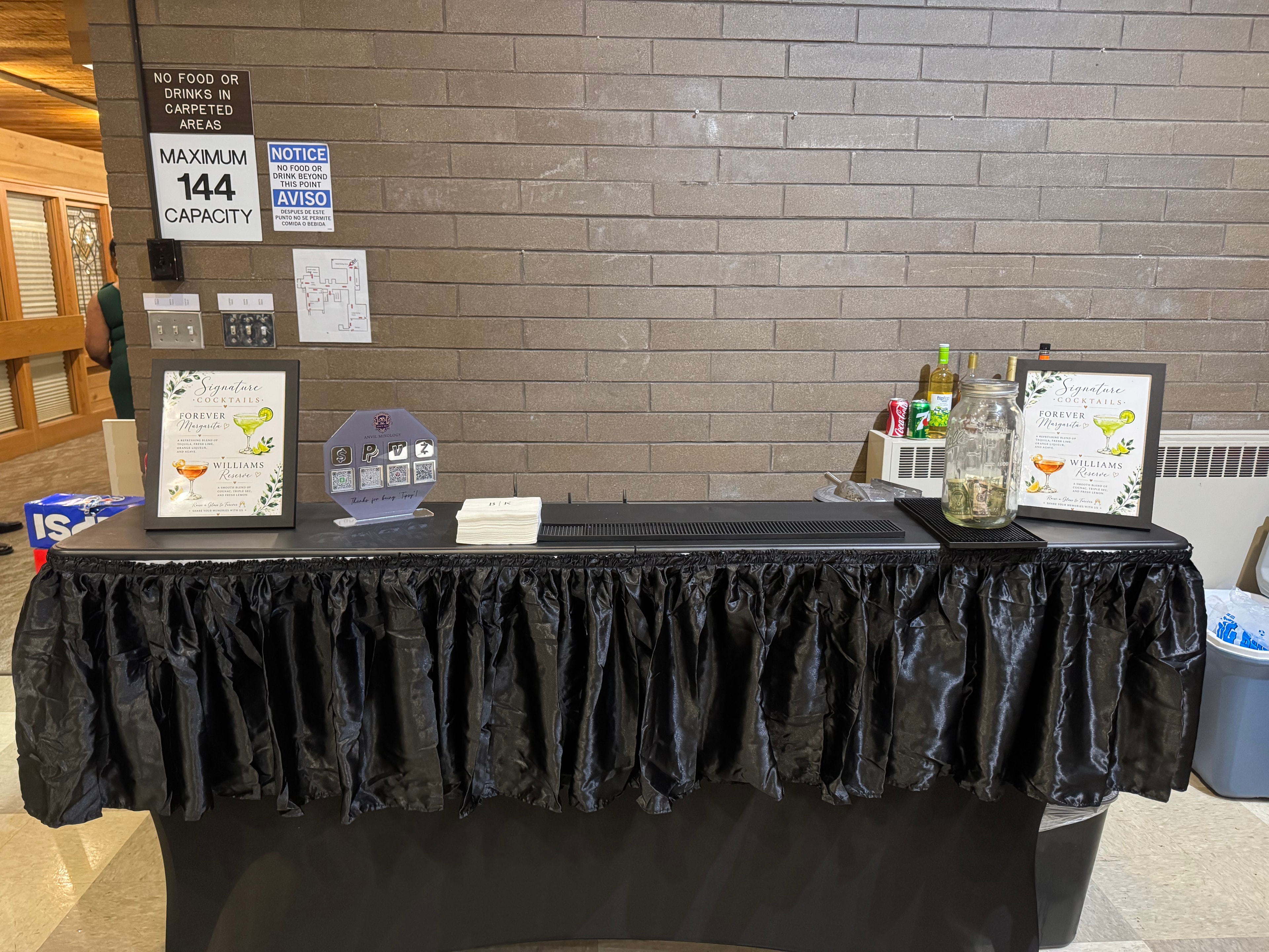 Anvil Mixology bar setup with signature cocktail menus and tip jar at the Bryan & Kristiane wedding, Sept 19 2026