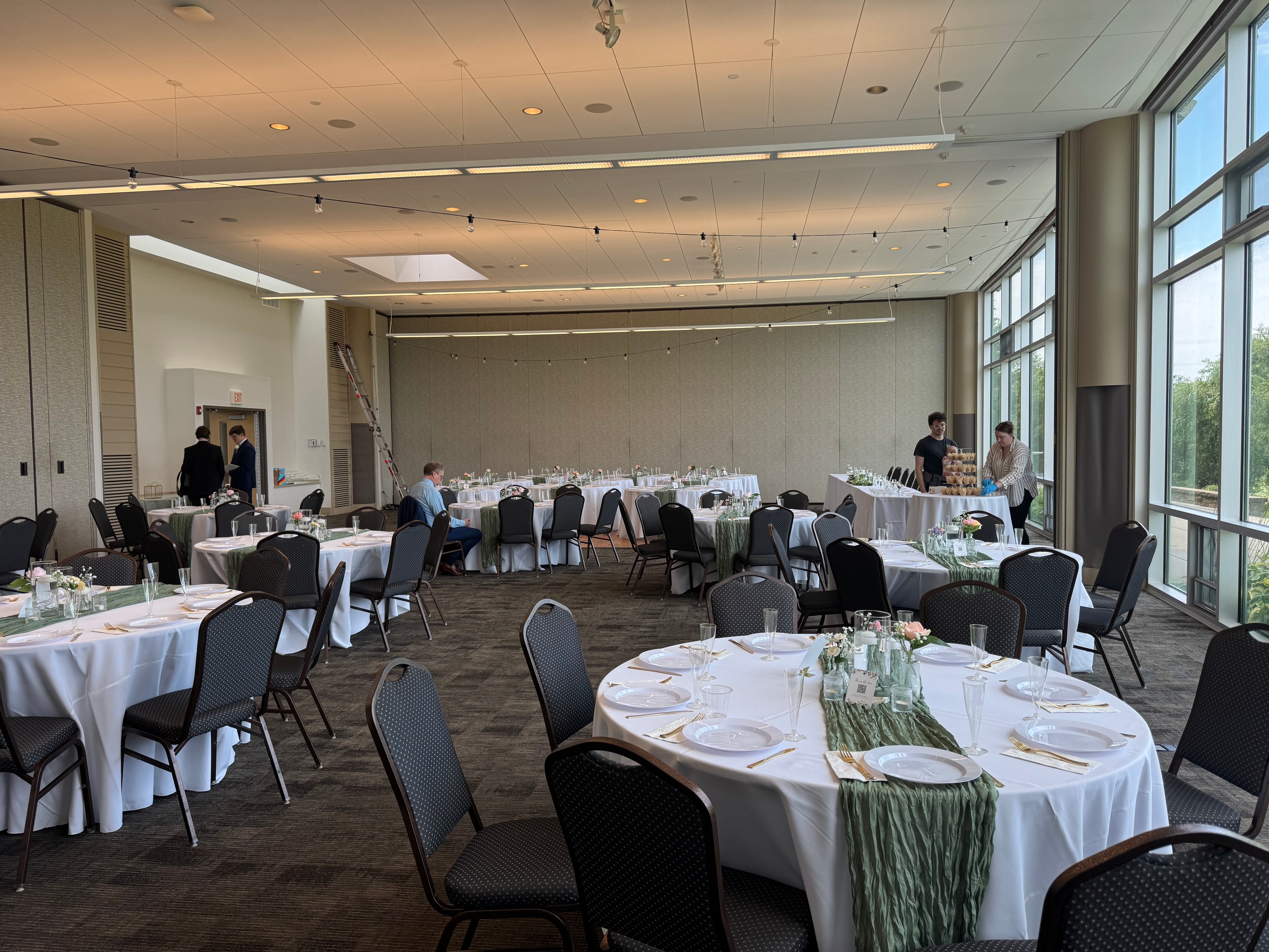 Elegant wedding reception hall with round tables, sage green runners, and floral centerpieces in North Chicago
